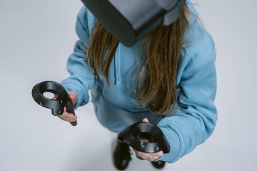 Woman wearing VR headset and using controllers, immersed in virtual reality gaming experience.