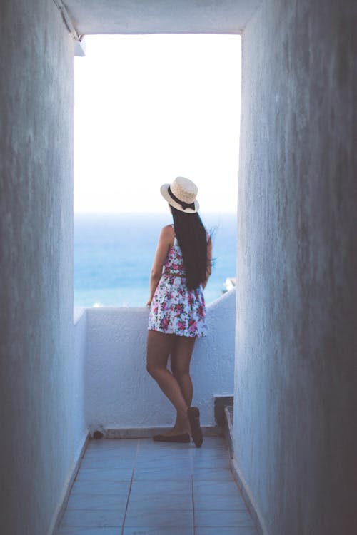 Woman in Pink Floral Midi Dress Standing on Balcony