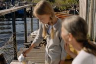 Woman in White Long Sleeve Shirt Sitting on Brown Wooden Dock