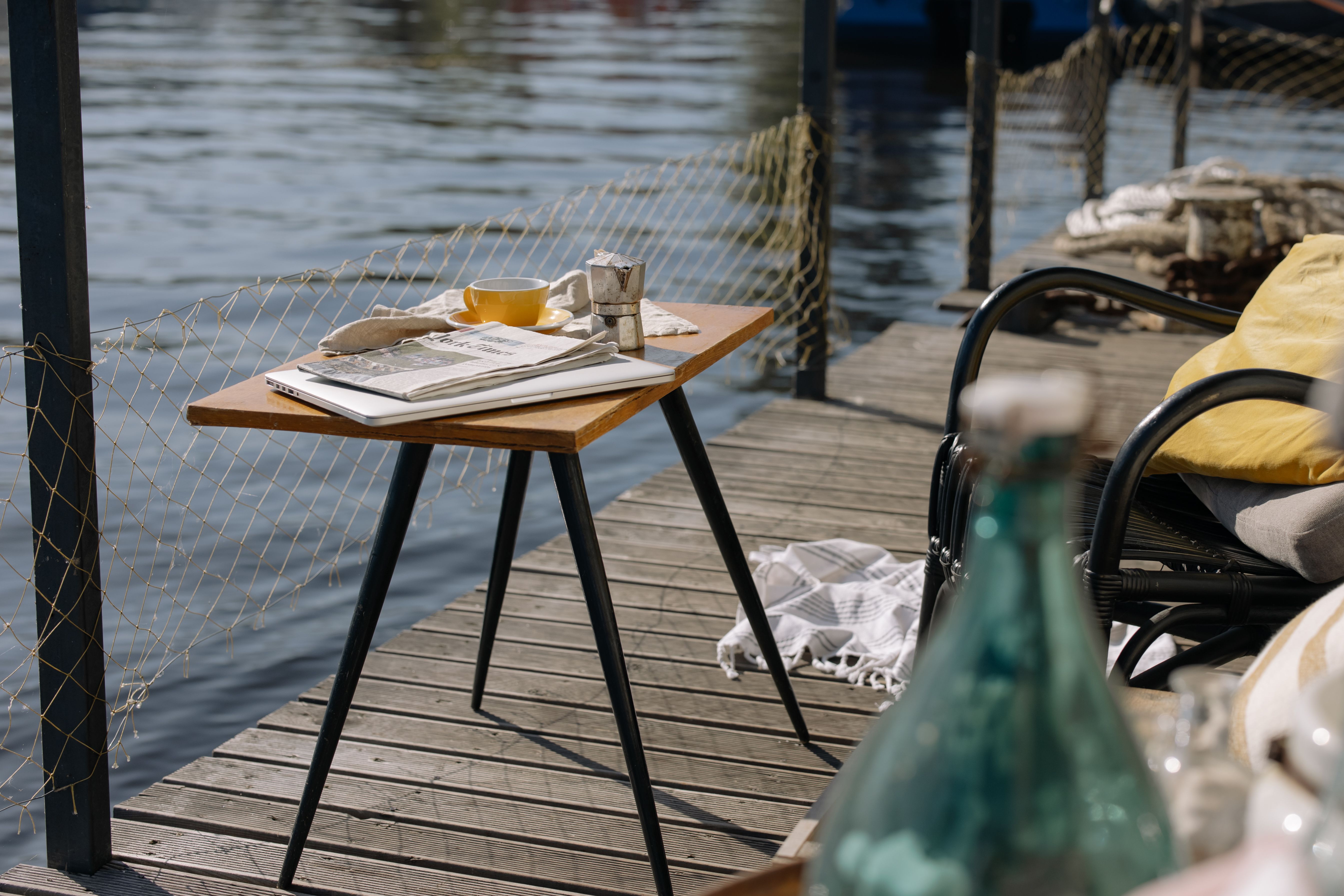 Old European village street with a laptop bag slung over a chair, morning light, and a coffee cup on a wooden table