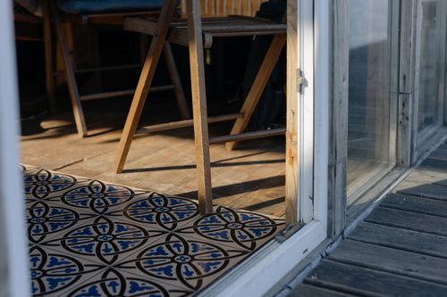 Free Wooden chair by a decorative tiled floor in a sunlit room, creating a warm, rustic atmosphere. Stock Photo