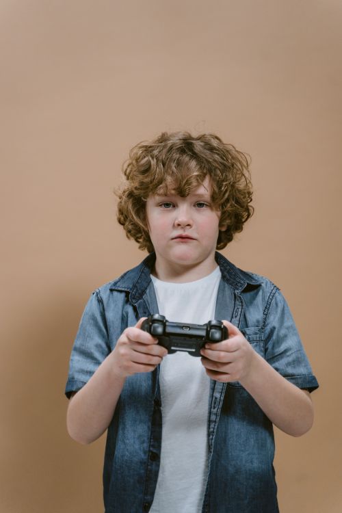Free Young boy enjoying video gaming with a controller, casual attire, focused expression. Stock Photo