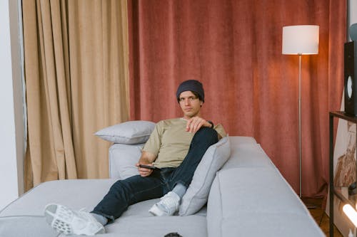 A Man Holding a Mobile Phone While Sitting on a Sofa
