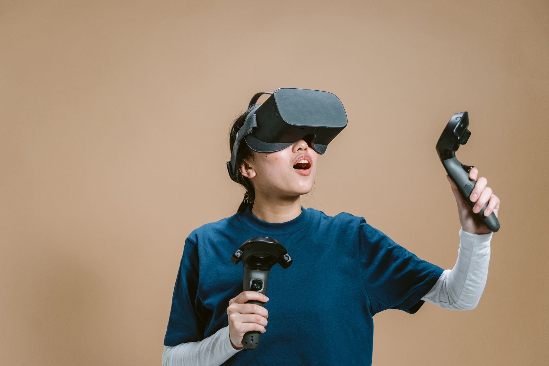 Woman experiencing virtual reality with headset and controllers in a studio setting.