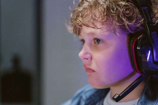 Close-up of a boy wearing headphones, deeply engaged in playing video games.