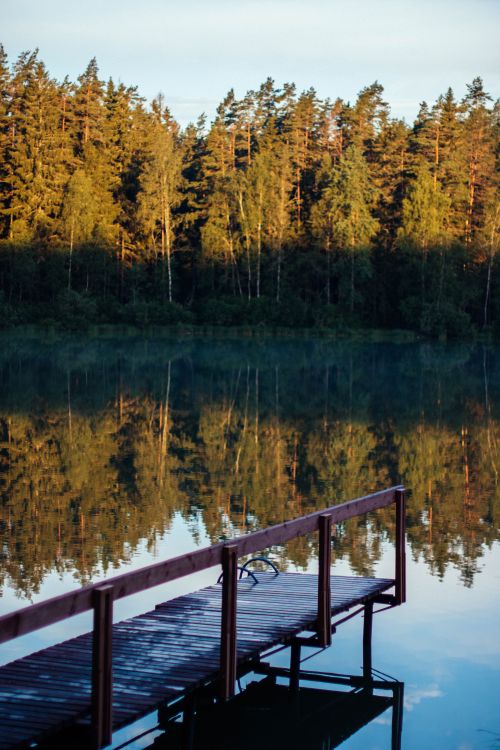 Free Tranquil lake with dock and forest reflection during fall season, perfect for nature enthusiasts. Stock Photo