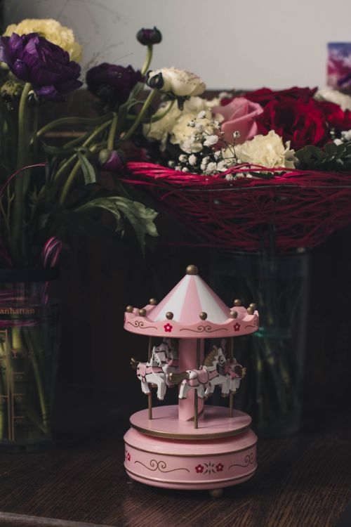 Free A beautiful floral display featuring a small pink carousel and vibrant blooms for interior decor. Stock Photo