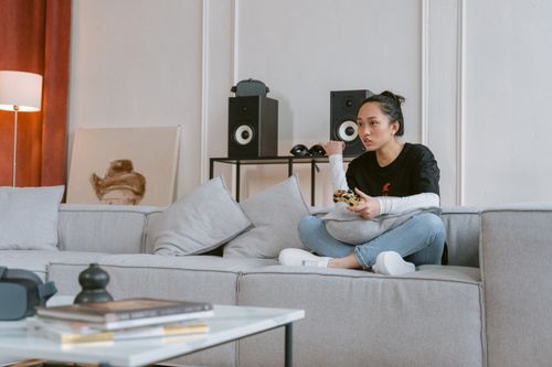 Free Young woman enjoying video games on a sofa in a stylish living room setting. Stock Photo