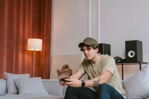 Free A young man playing video games on a sofa indoors, with a focus on leisure and technology. Stock Photo