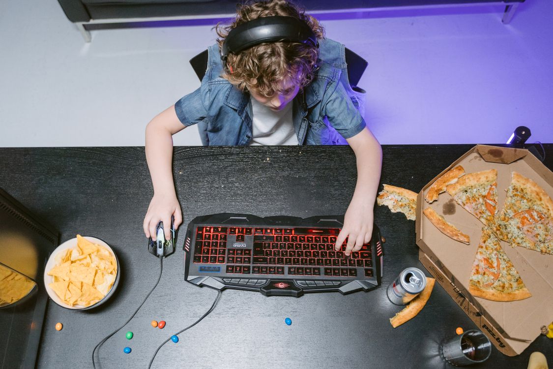 A Kid Wearing Headset Sitting at a Table Playing a Computer Game · Free ...