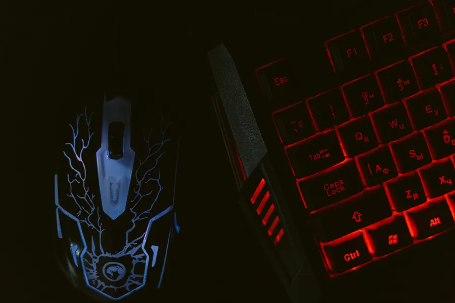 futuristic gaming keyboard and mouse glowing blue and cyan in a dark room