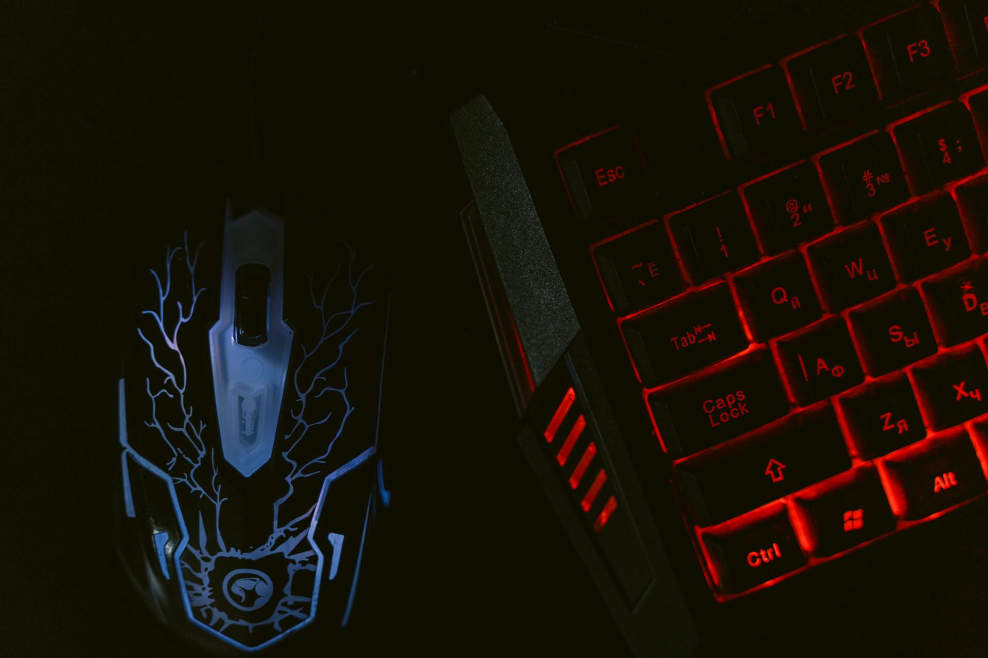 Close-up of a glowing gaming mouse and a backlit keyboard in a dim setting, showcasing a tech-savvy setup.