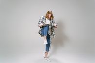 Woman in White and Black Long Sleeve Shirt and Blue Denim Jeans Standing and Holding Black