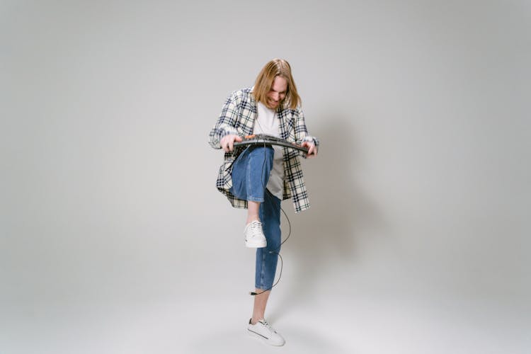 A Man In White And Black Plaid Shirt And Blue Denim Jeans Breaking Computer Keyboard