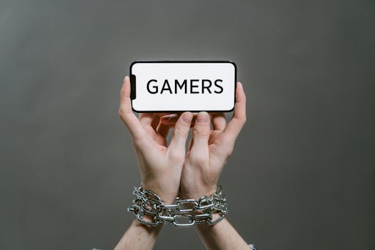 Conceptual image of a person holding a smartphone labeled 'GAMERS' with chained hands.