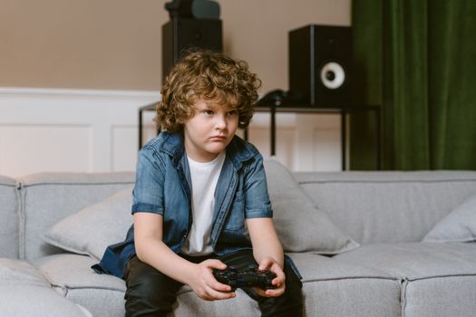 A Boy Playing Video Games while Sitting on a Sofa