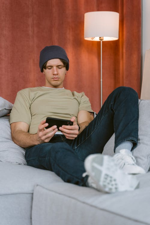 Man Sitting on the Sofa Holding a Mobile Phone