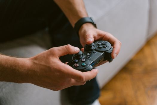 Hands holding a game controller while playing video games indoors, a leisure activity.