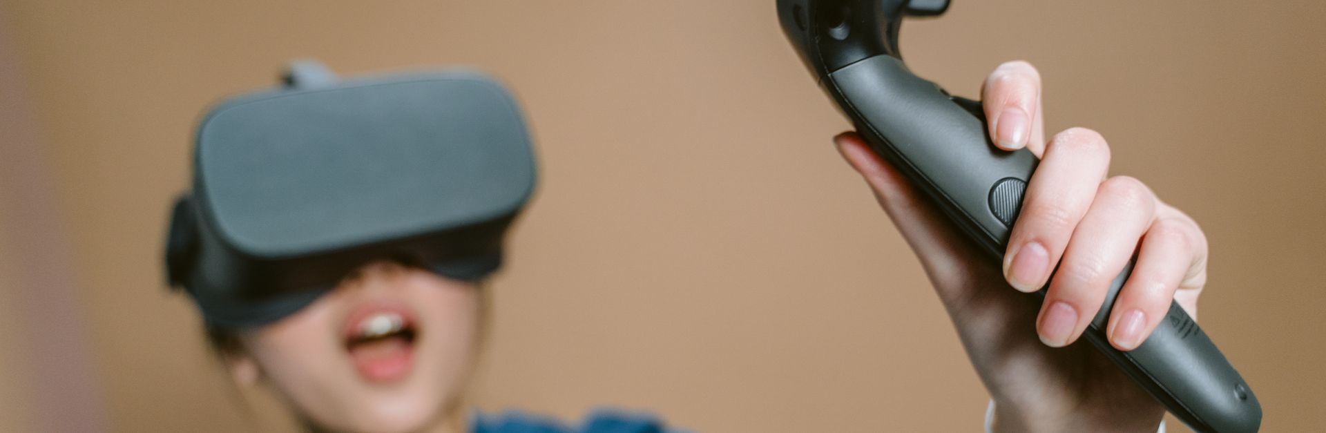 Enthusiastic woman using VR headset and controller indoors.