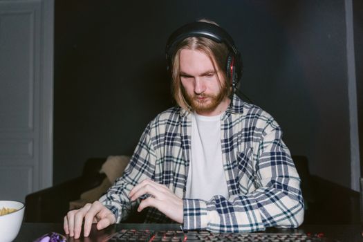 Focused gamer playing on computer with headset in a dark room.