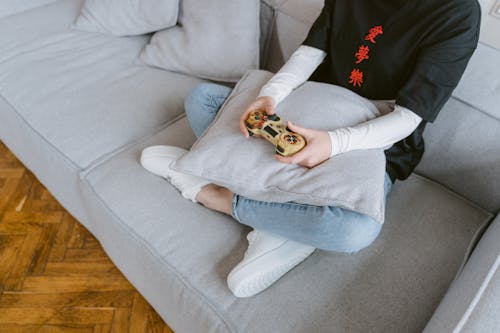 A Person Sitting on a Sofa while Holding a Video Game Controller