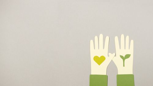 Free Paper cutout hands with eco symbols on gray background, symbolizing love and growth. Stock Photo