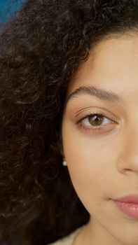 A detailed headshot showing half a face and eye of a woman with curly hair.