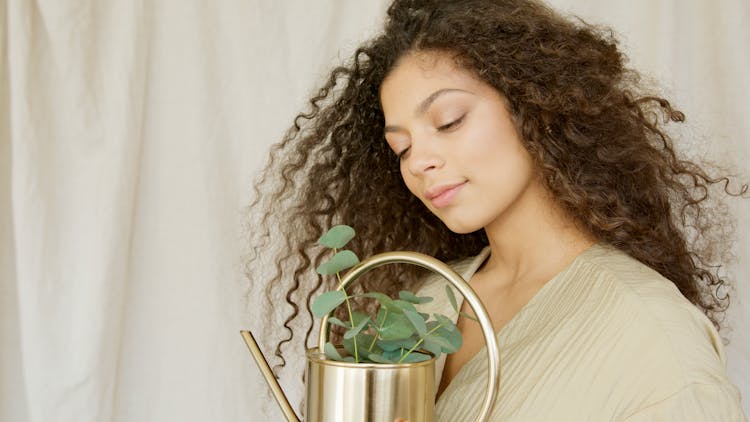 Woman Holding Stainless Gold Watering Can With Green Plant