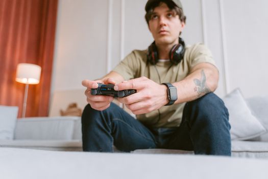 Young man focused on video gaming at home wearing headphones and a smartwatch.