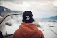 在德国白雪皑皑的奥尔施塔特，一个人站在汽车旁，欣赏着冬季的山脉