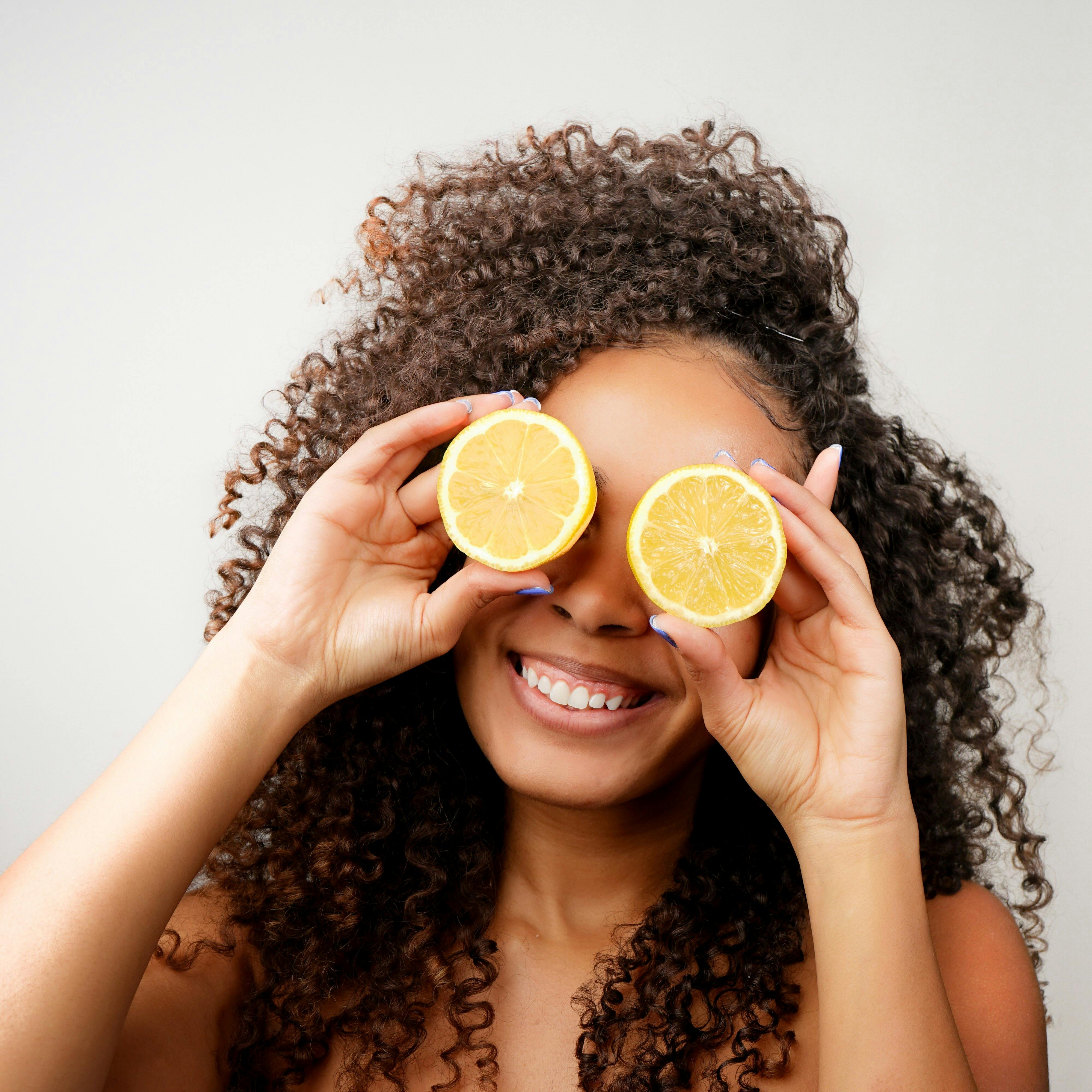 A Woman Holding Lemon Slice Covering Her Eyes