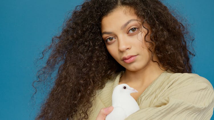 A Woman Holding Closely A White Bird