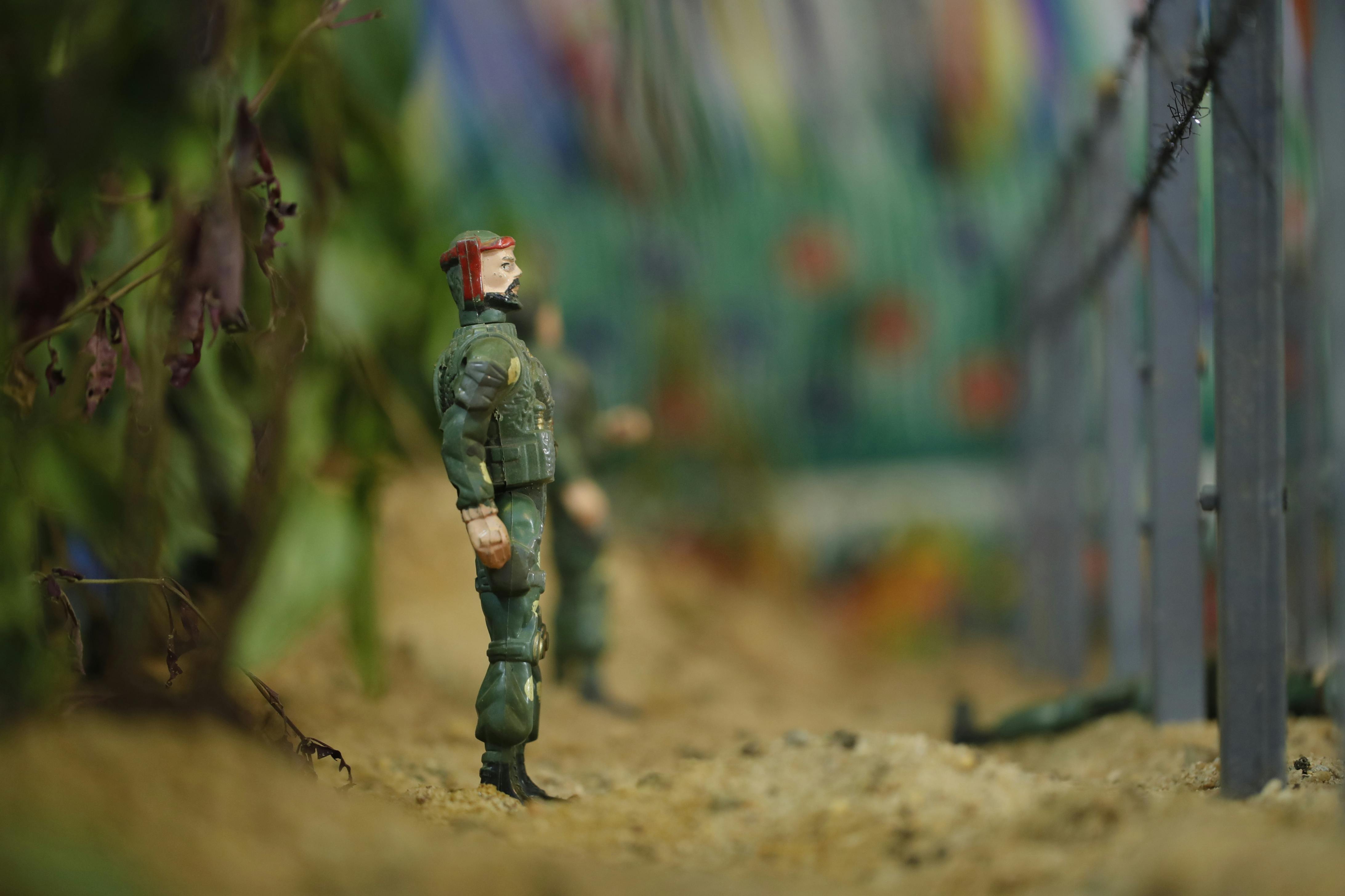 Close-up of toy soldiers in military uniform standing in a simulated environment with blurred background.