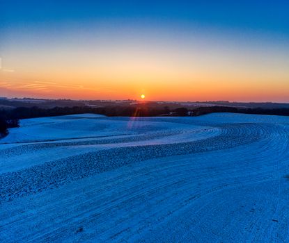 A beautiful winter sunrise over snow-covered fields in Minnesota, USA, showcasing nature's tranquility.