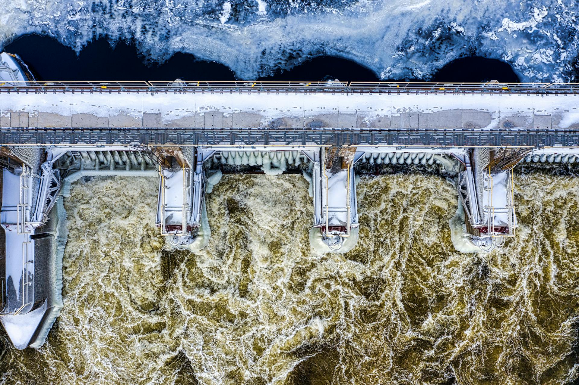 A stunning aerial view of a snow-covered dam with rushing water in Minnesota during winter.