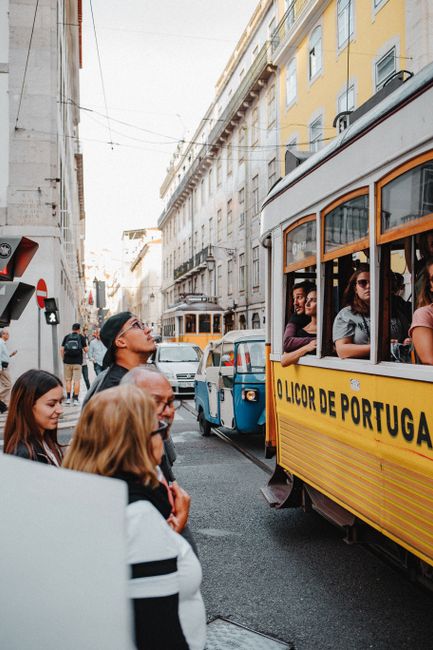A lively street in Lisbon showcasing classic yellow trams and local architecture.