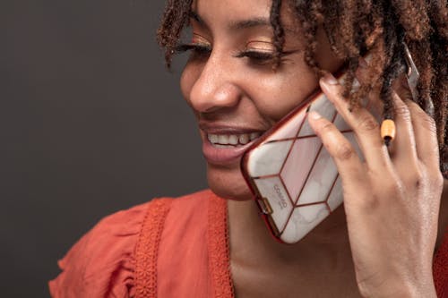 Close-Up Photo of a Woman with Dreadlocks Smiling while Talking on Her Phone