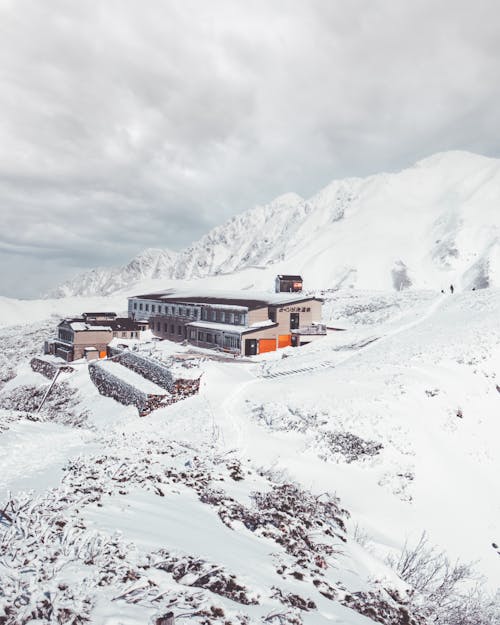 Buildings on Snow Covered Field Near Mountain