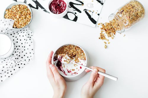 Person Mixing Cereal, Milk, and Strawberry Jam on White Ceramic Bowl