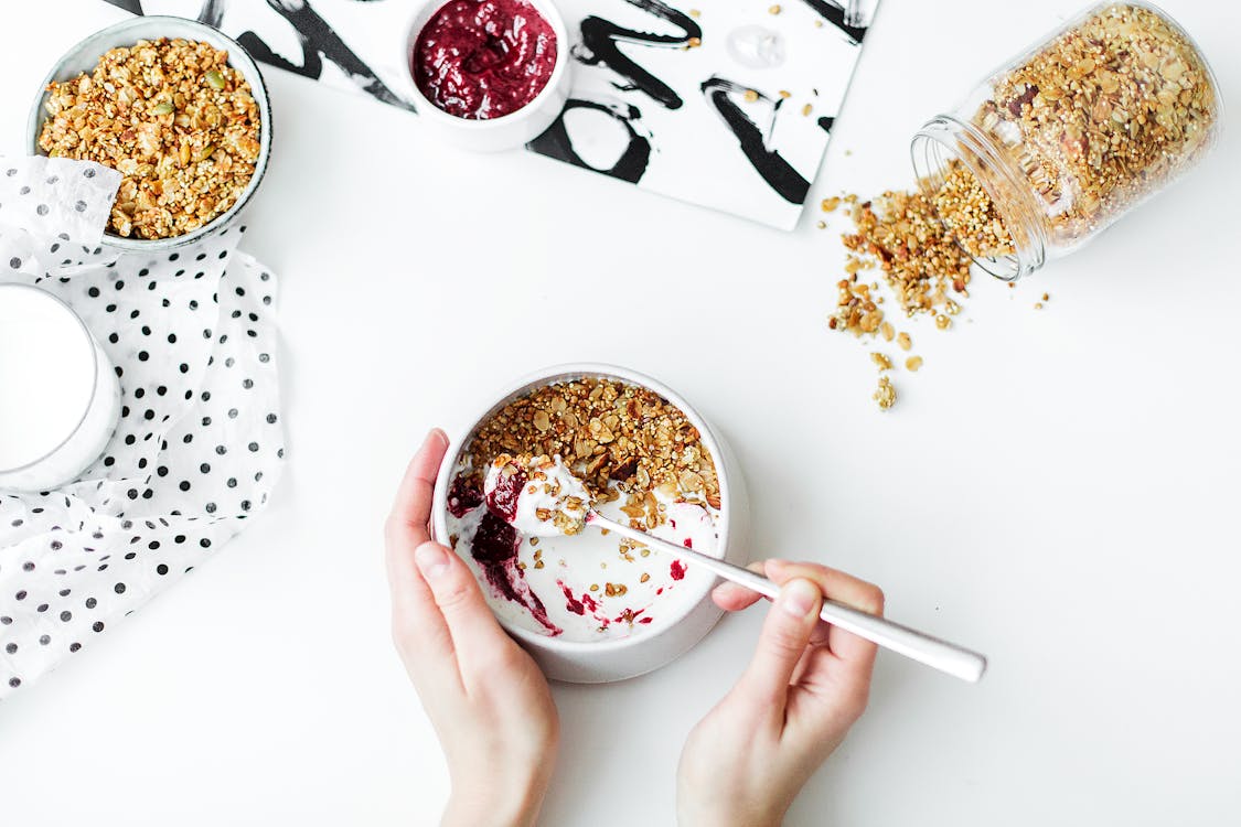 Free Person Mixing Cereal, Milk, and Strawberry Jam on White Ceramic Bowl Stock Photo