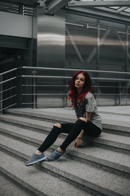 Woman in Black Ripped Pants Sitting on Concrete Stairs