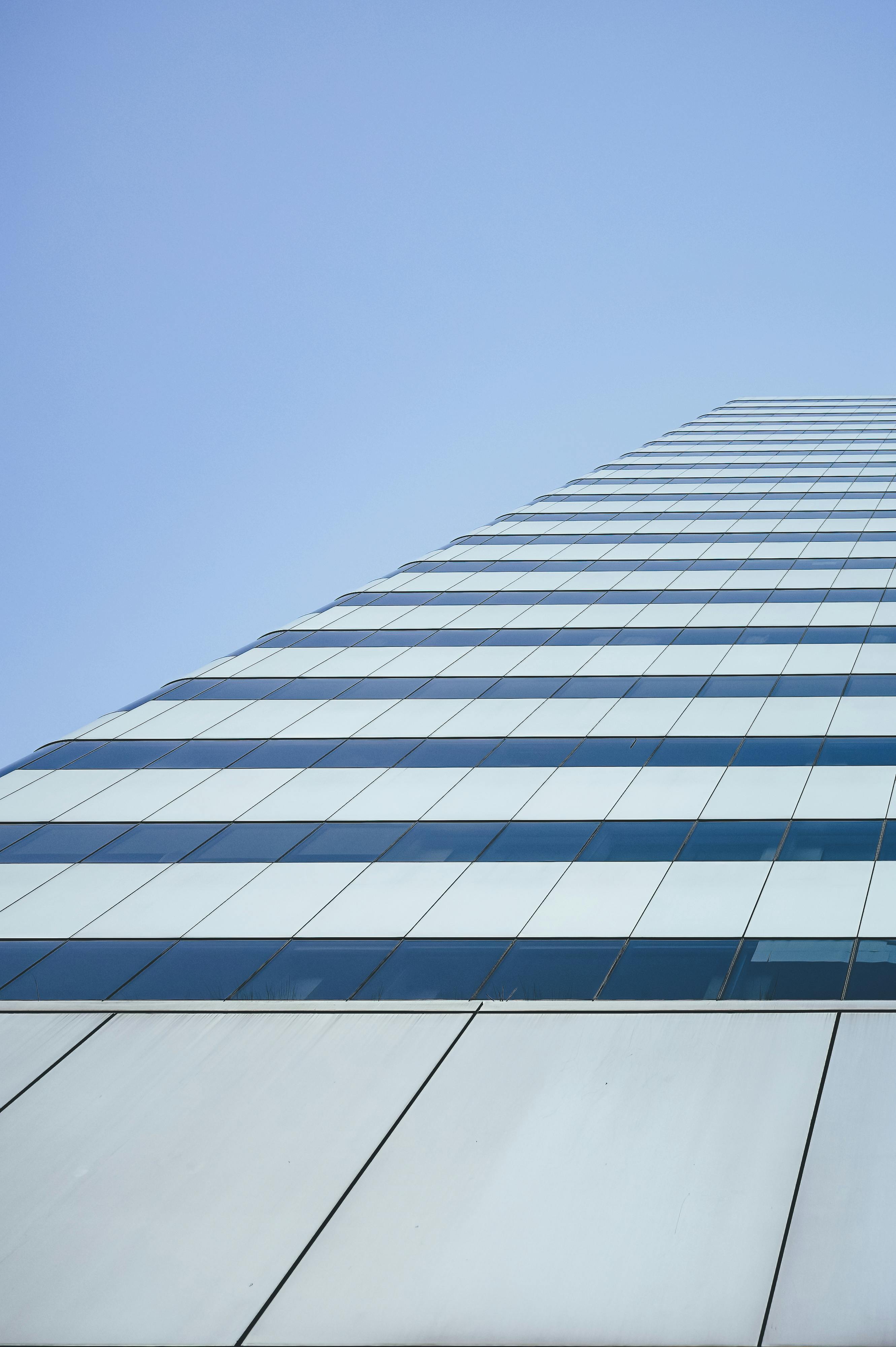 Low angle of geometric facade of modern office building under clear blue sky on sunny day
