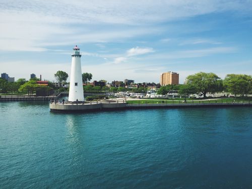 Free A beautiful view of a lighthouse by a bay with a city skyline in the background. Stock Photo