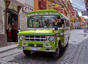 Green and White Volkswagen T-2 Van Parked Beside Brown Concrete Building