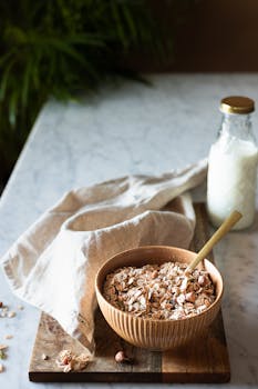 A cozy breakfast setup with cereal in a wooden bowl and a bottle of milk on a marble countertop.