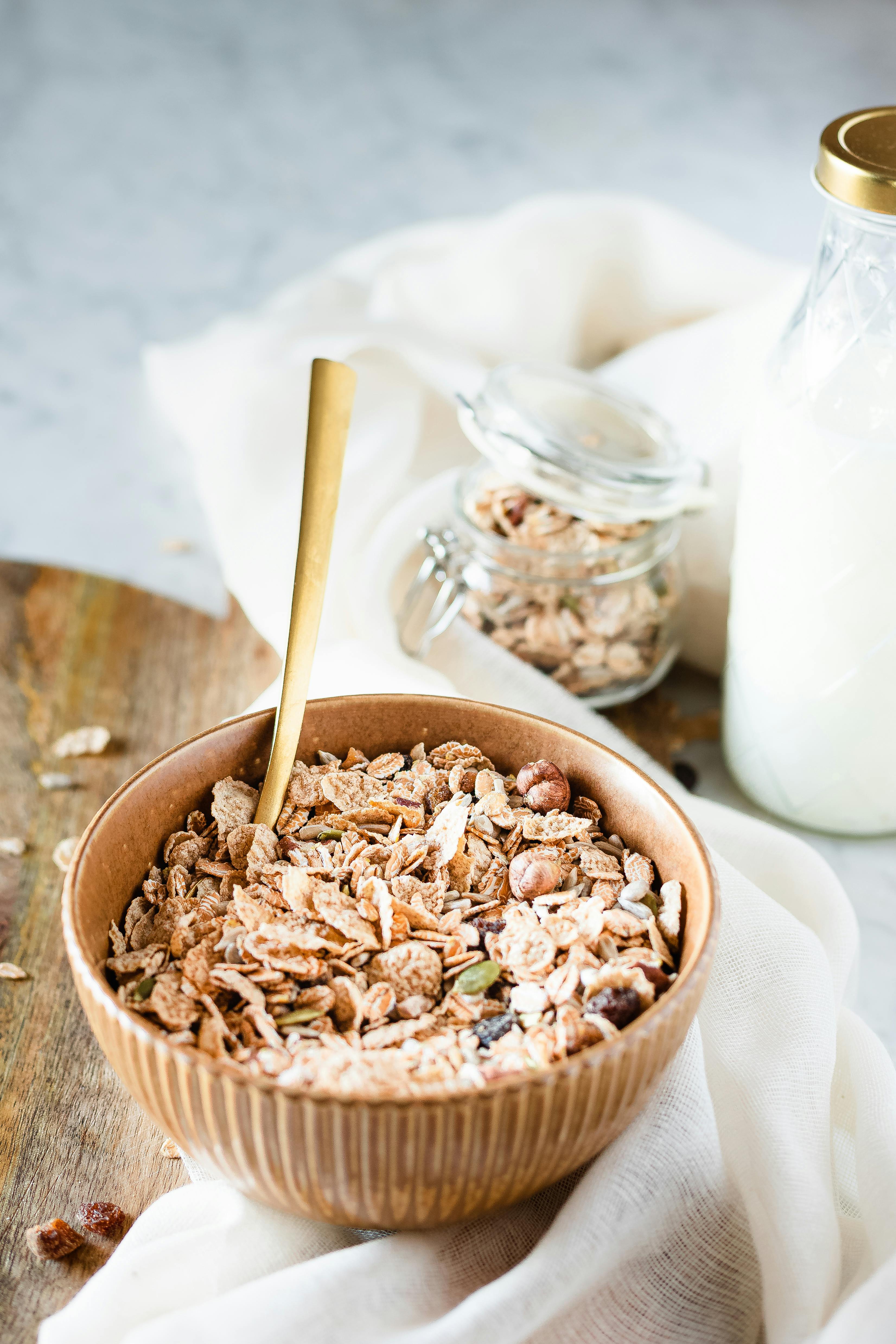 Nutritious breakfast cereal with seeds, milk, and nuts in a ceramic bowl on a white linen background.