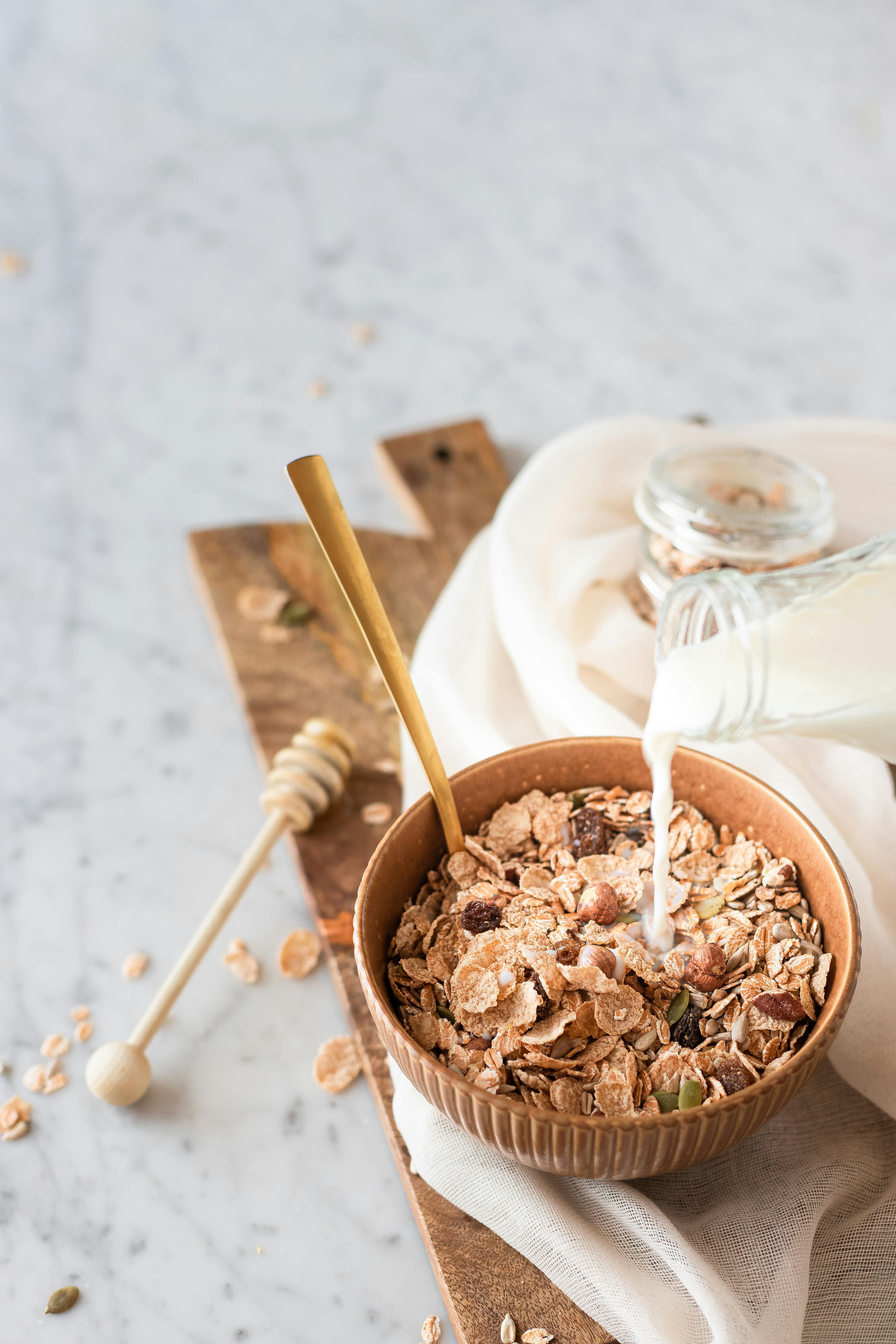 Close-up of a healthy breakfast with cereal, honey, and milk, styled on a rustic table.