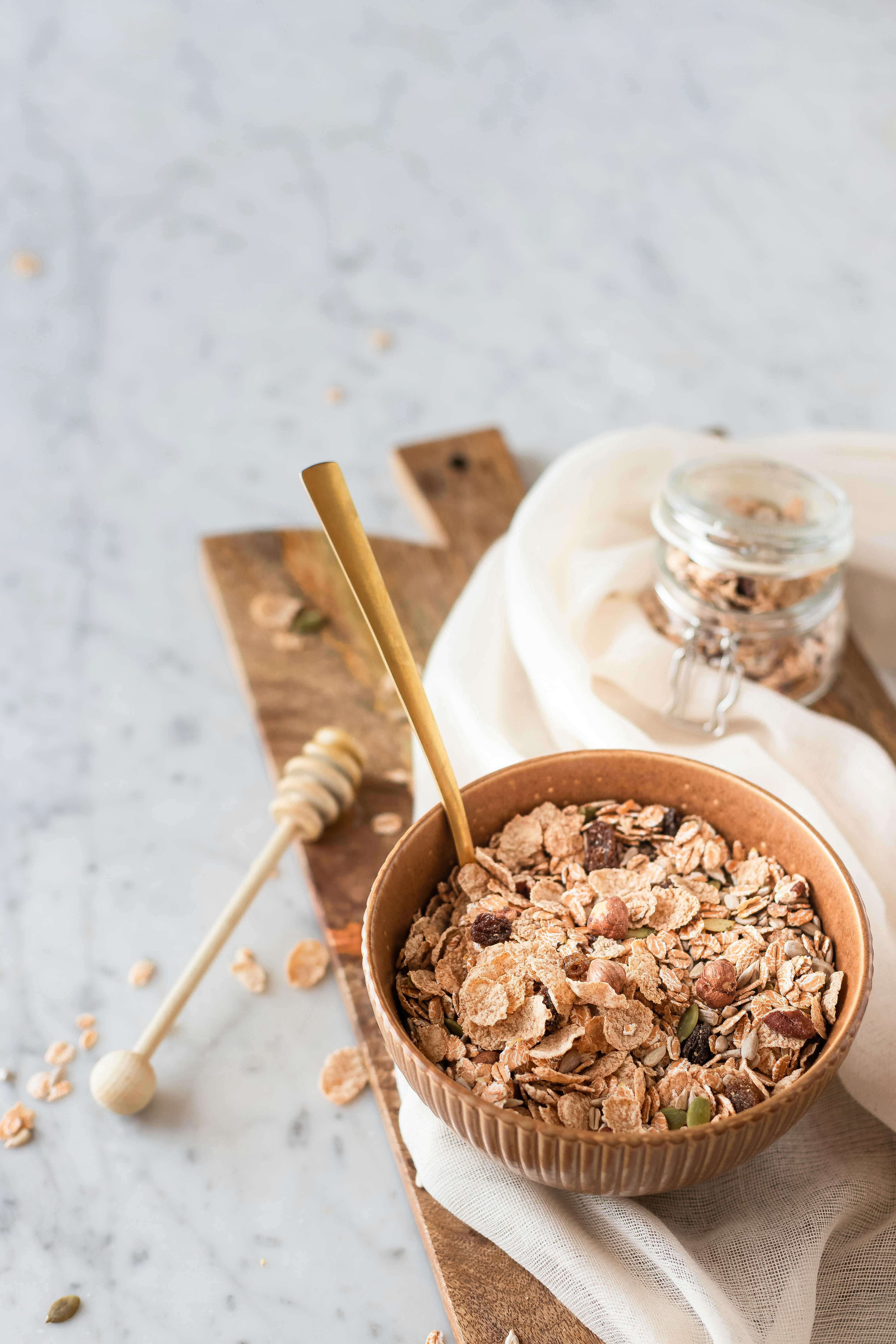A bowl of delicious granola with a honey dipper on a marble surface, ideal for healthy breakfast ideas.