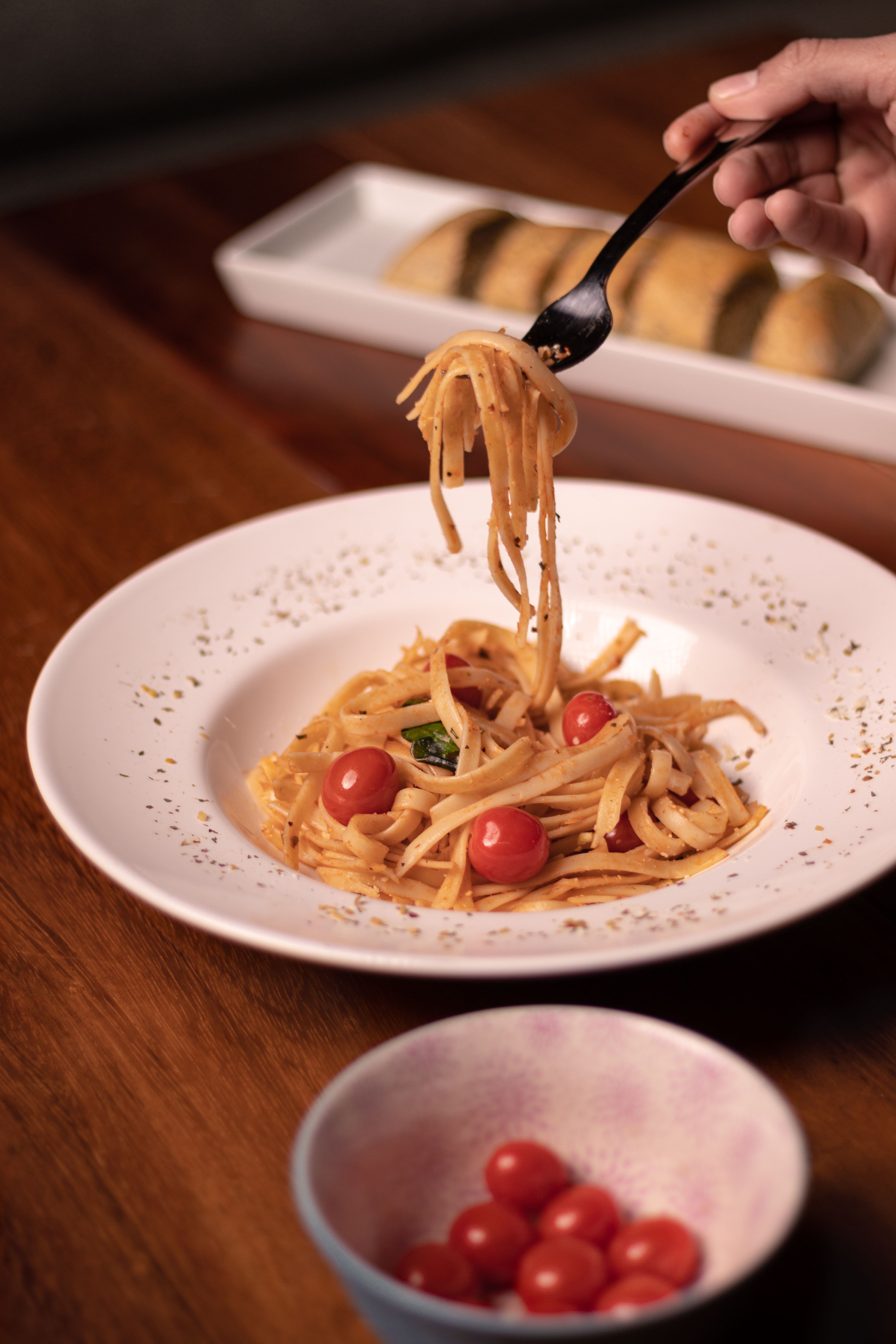 Savor a mouthwatering Italian pasta dish with fresh cherry tomatoes on a wooden table.