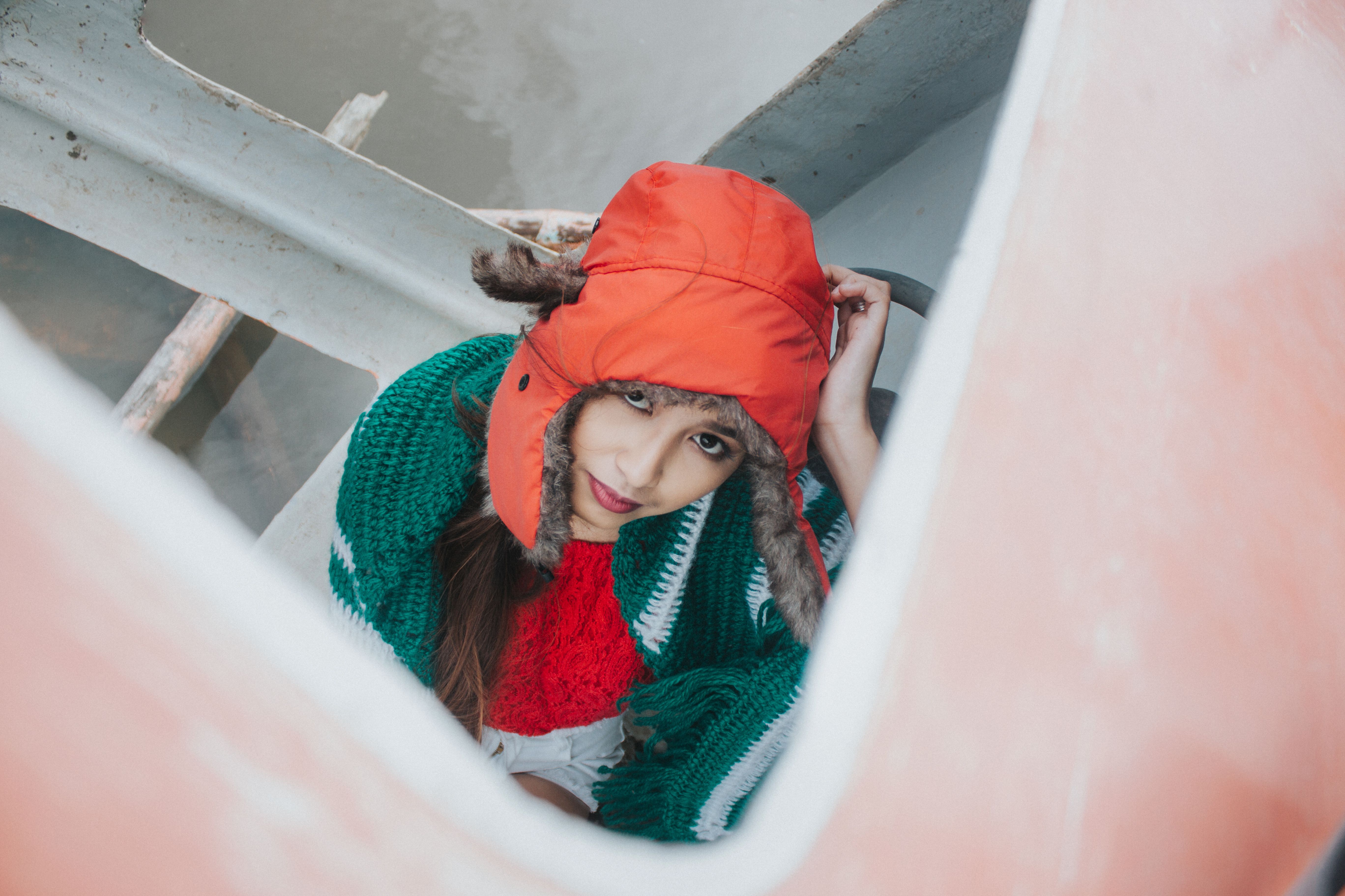 A woman in vibrant winter clothing gazes upward in a rustic setting.